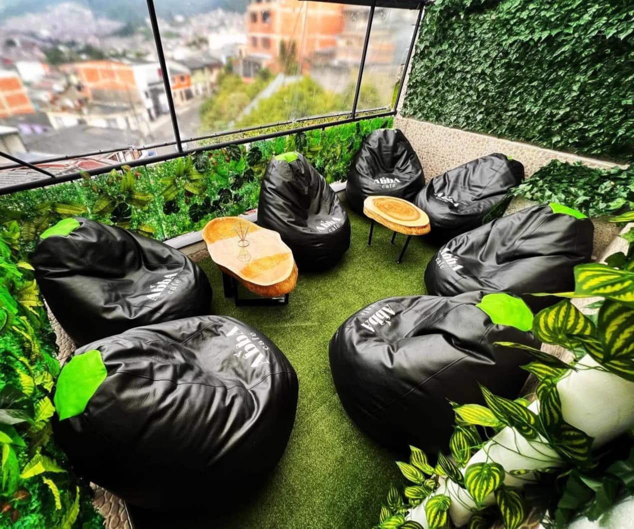 Terraza de Abba Café con puffs negros y vista a las montañas de Manizales