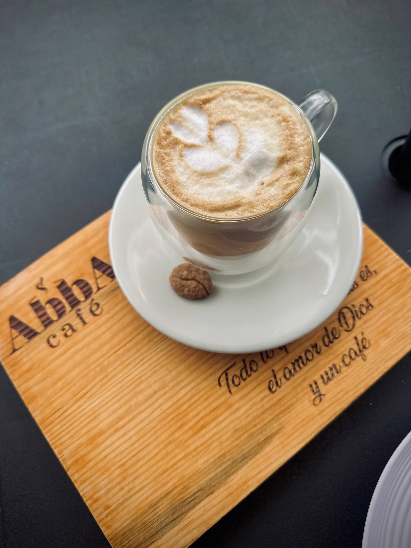 Cappuccino con latte art sobre tabla grabada de Abba Café