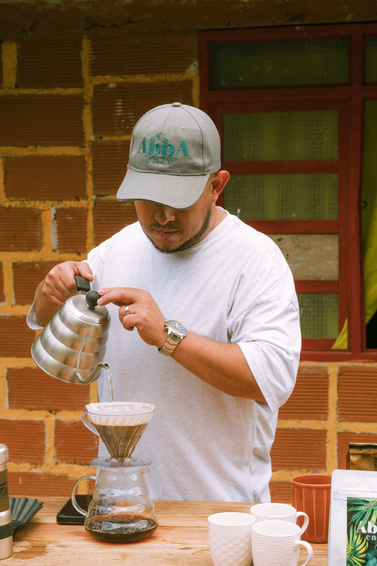 Alejo preparando café de origen en V60 en la finca, con la gorra de Abba Café